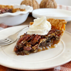 slice of grandma's pecan pie with whipped cream on a plate.