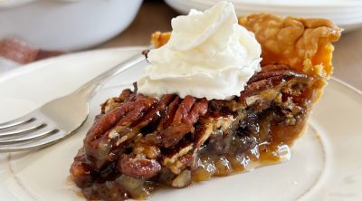 slice of grandma's pecan pie with whipped cream on a plate.
