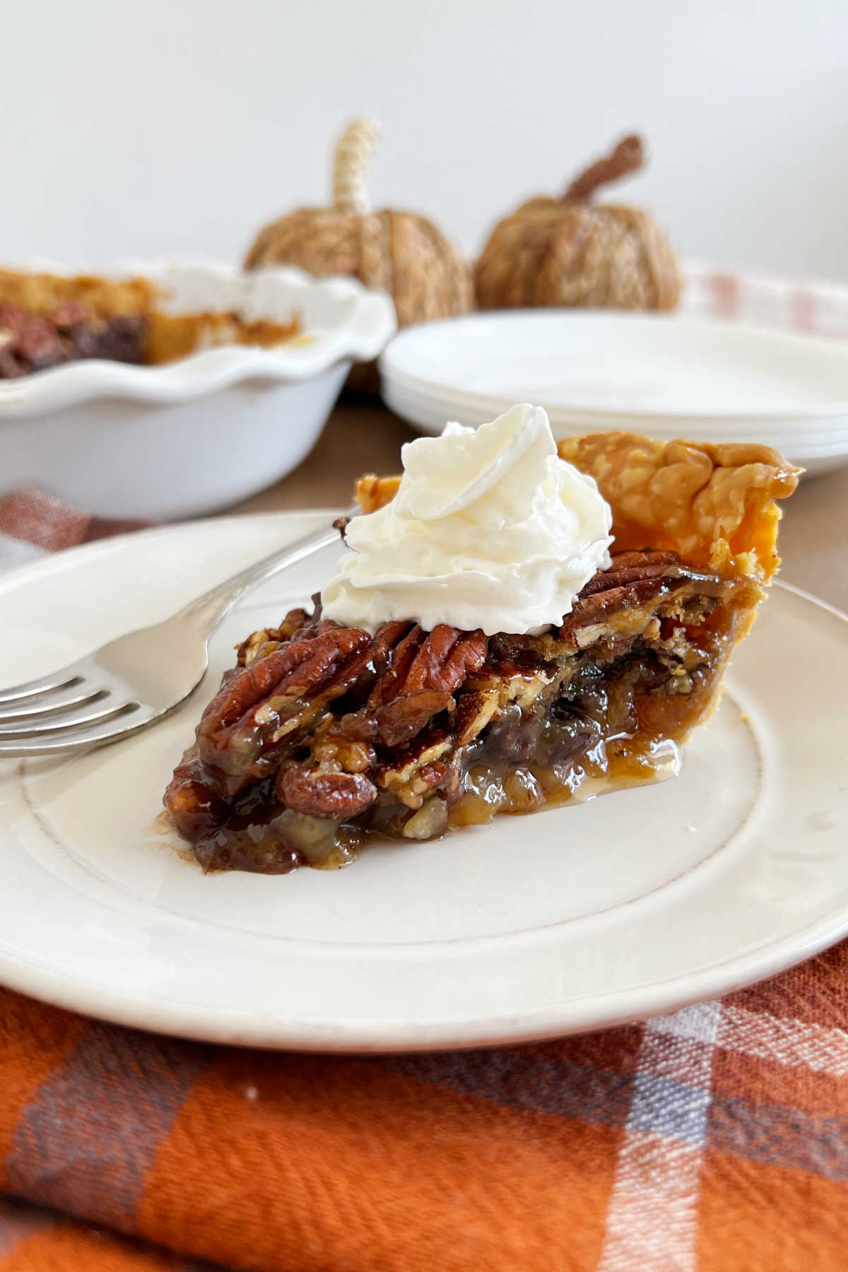 slice of grandma's pecan pie with whipped cream on a plate.