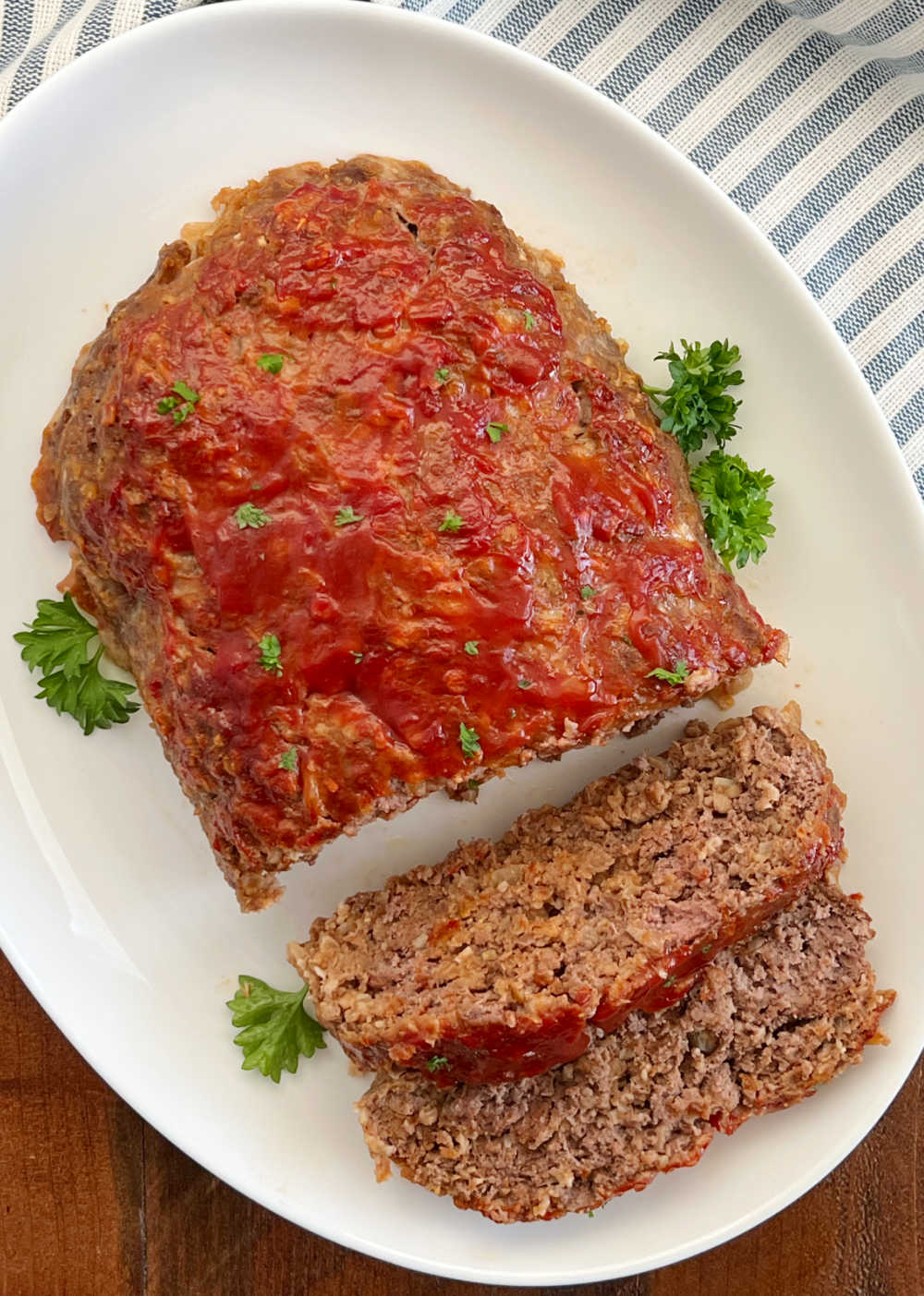 meatloaf with ketchup glaze and parsley on serving plate.