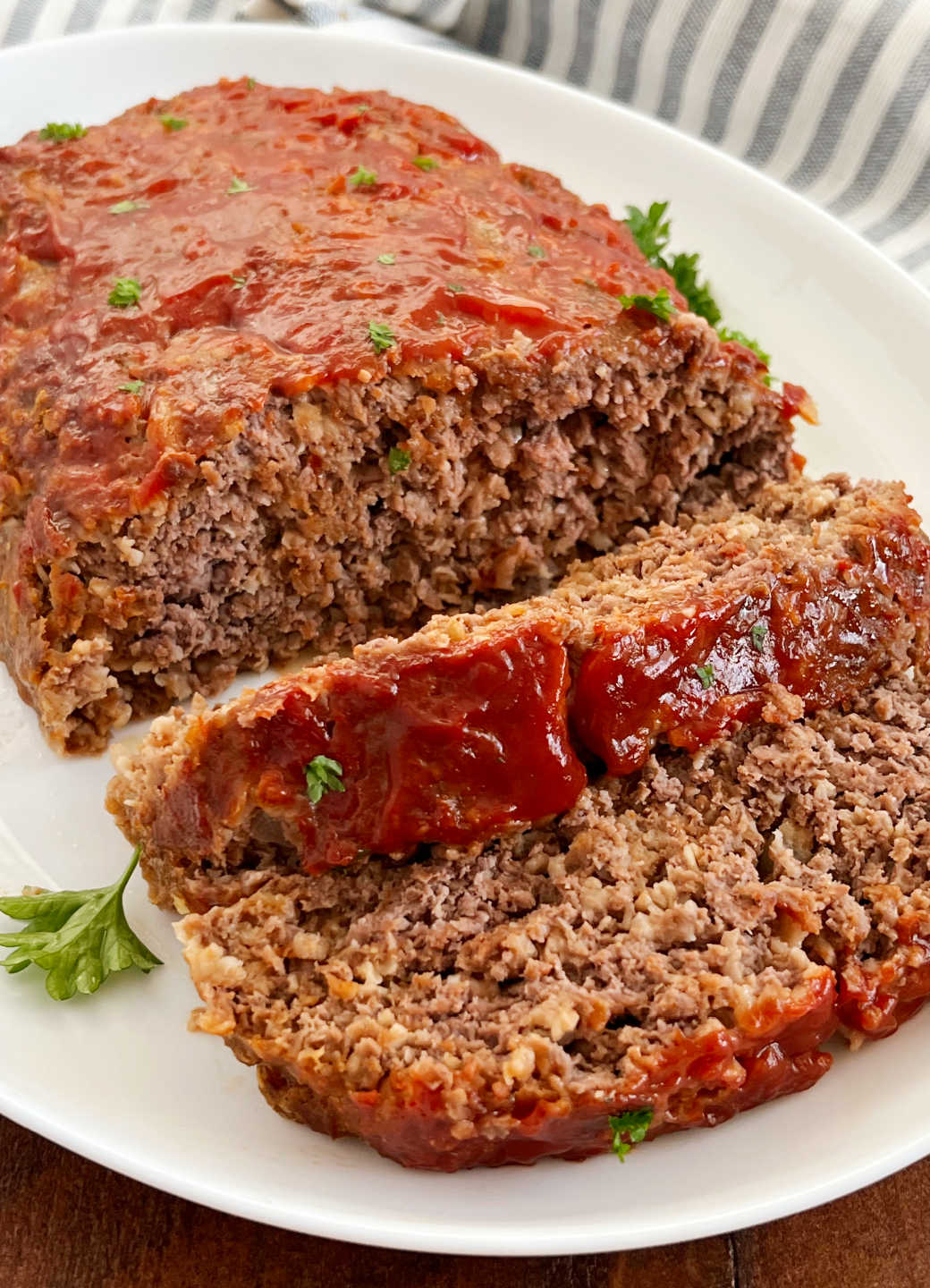 meatloaf with quaker oats and ketchup glaze sliced on a white platter.