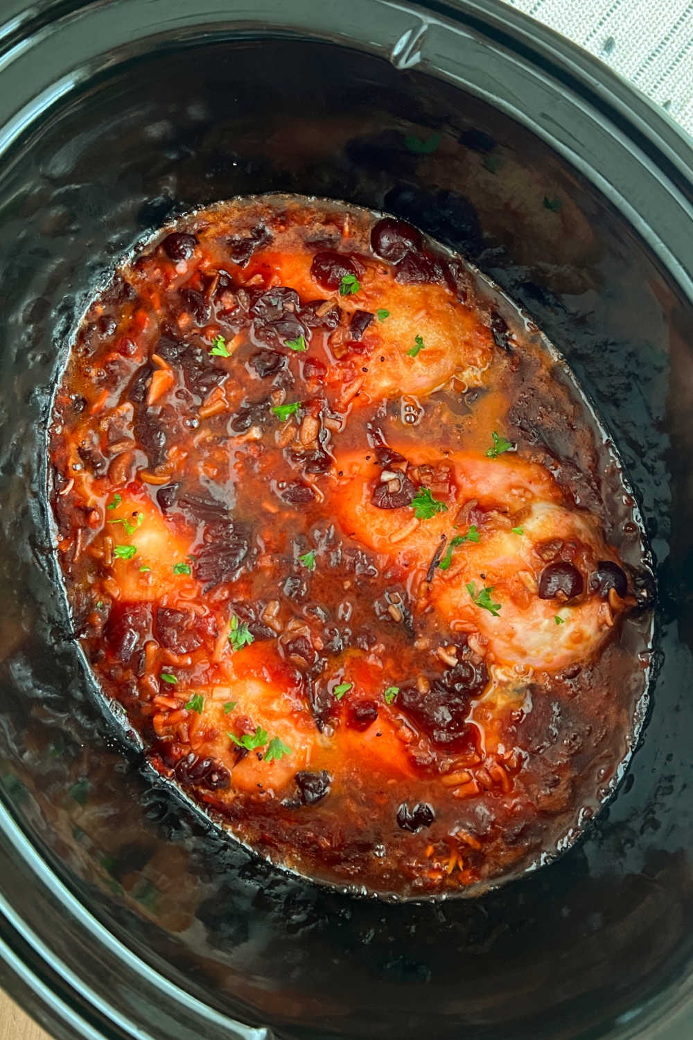 slow cooker cranberry chicken with whole berries and sauce in crock pot.