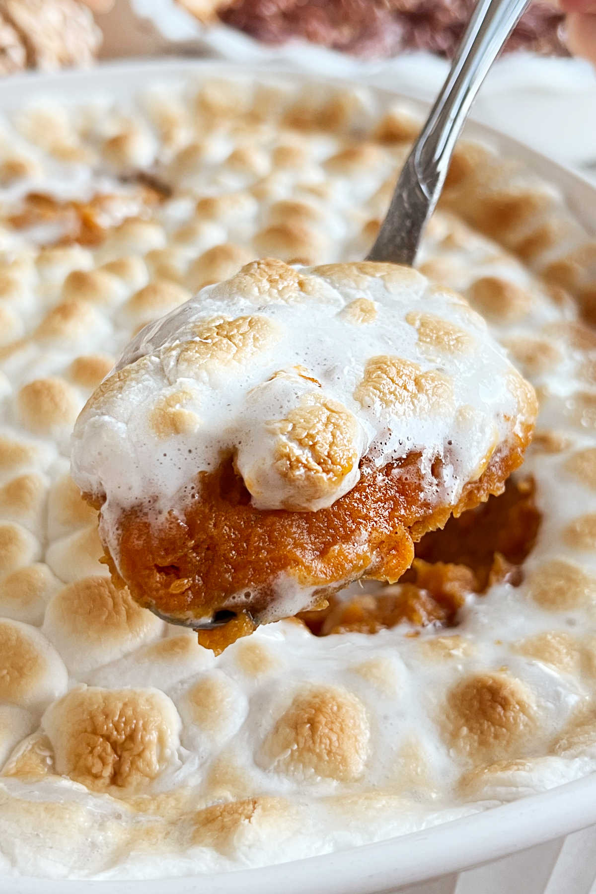 eggless sweet potato casserole with broiled marshmallow topping on serving spoon.