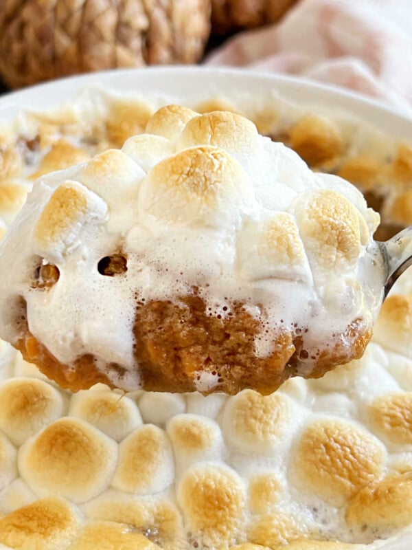 sweet potato casserole made with canned yams and marshmallows on serving spoon.