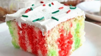 Christmas jello poke cake with cool whip frosting on plate.