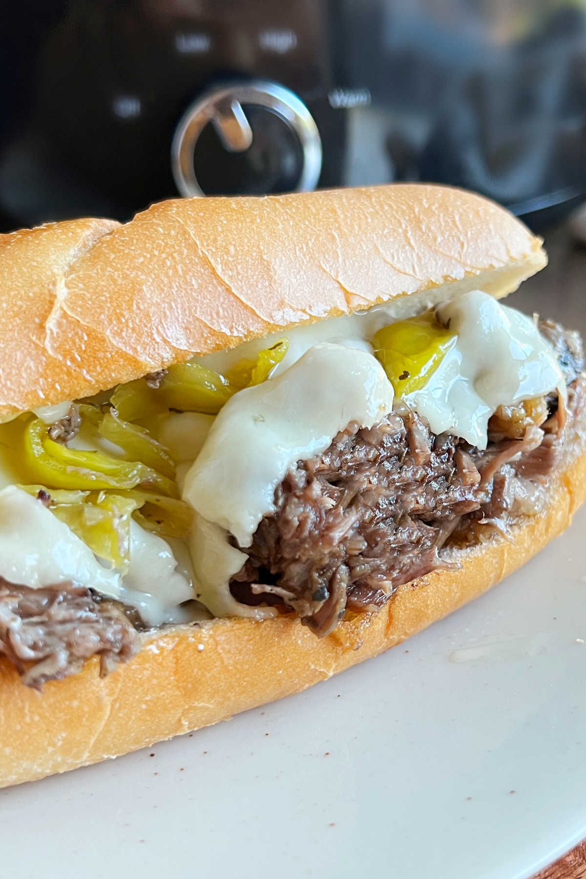 Italian beef sandwich with melted cheese on a plate.
