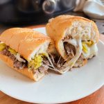 crock pot Italian beef sandwiches with gooey melted provolone cheese on a plate.