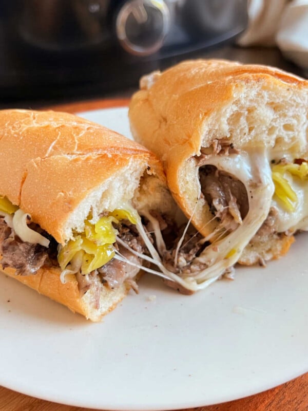 crock pot Italian beef sandwiches with gooey melted provolone cheese on a plate.
