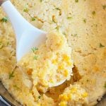 crock pot corn casserole with Jiffy Mix on a whit serving spoon.
