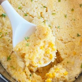 crock pot corn casserole with Jiffy Mix on a whit serving spoon.