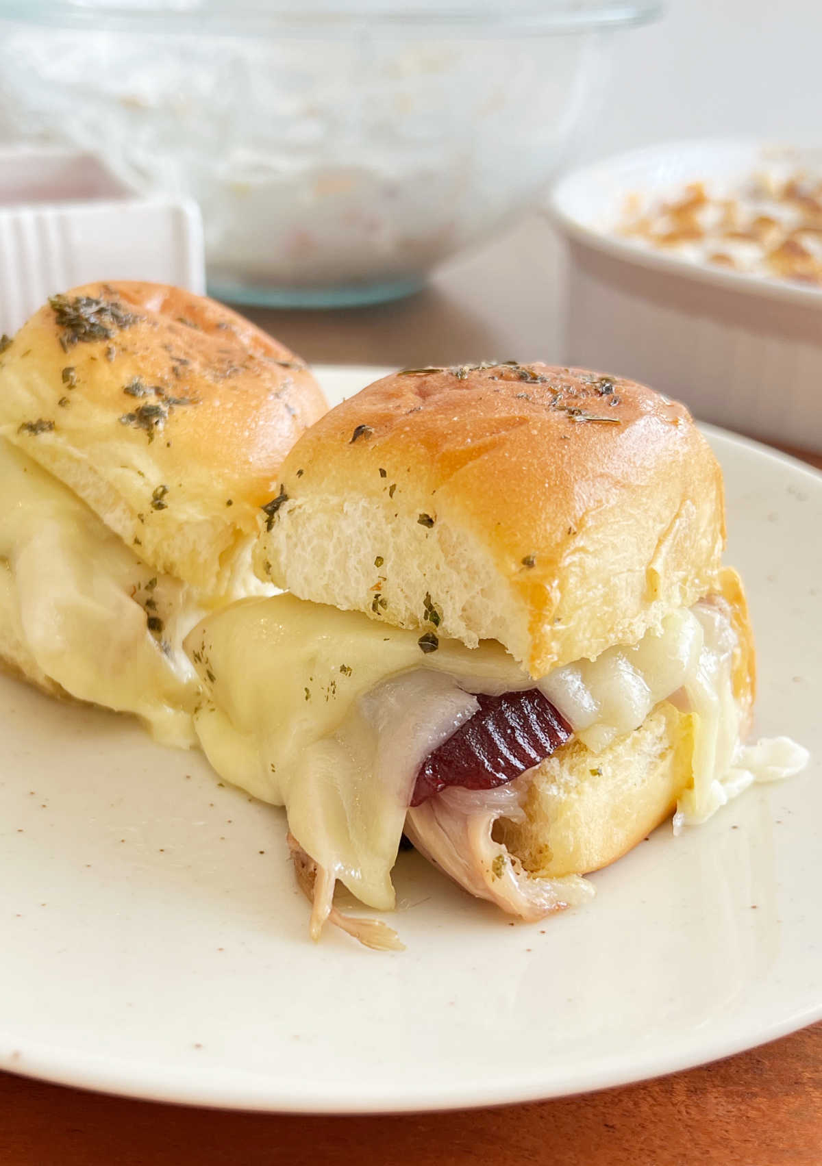 turkey sliders on Hawaiian rolls with cranberry sauce and provolone cheese on plate.
