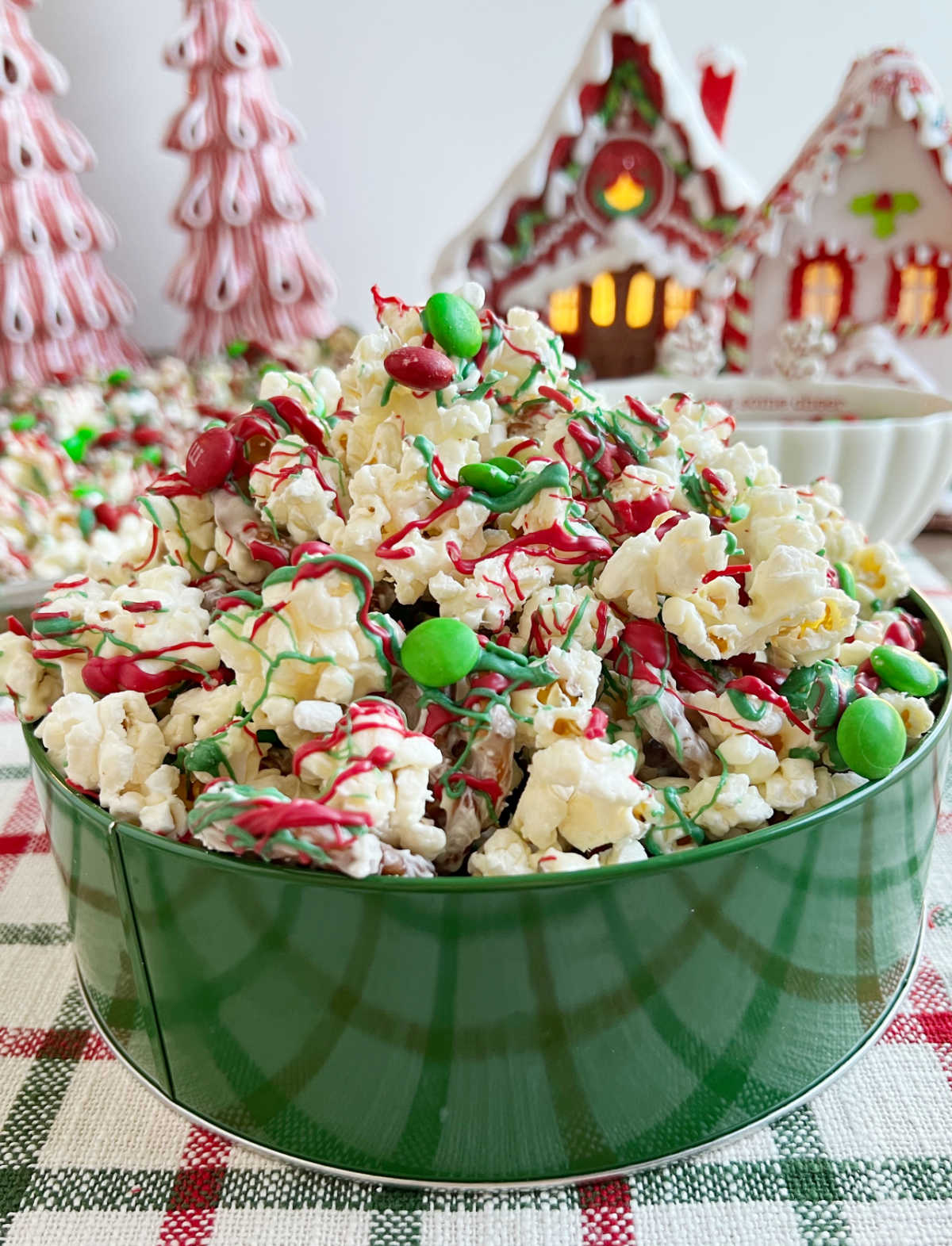 container of Christmas crunch with popcorn and pretzels and candy on the table.
