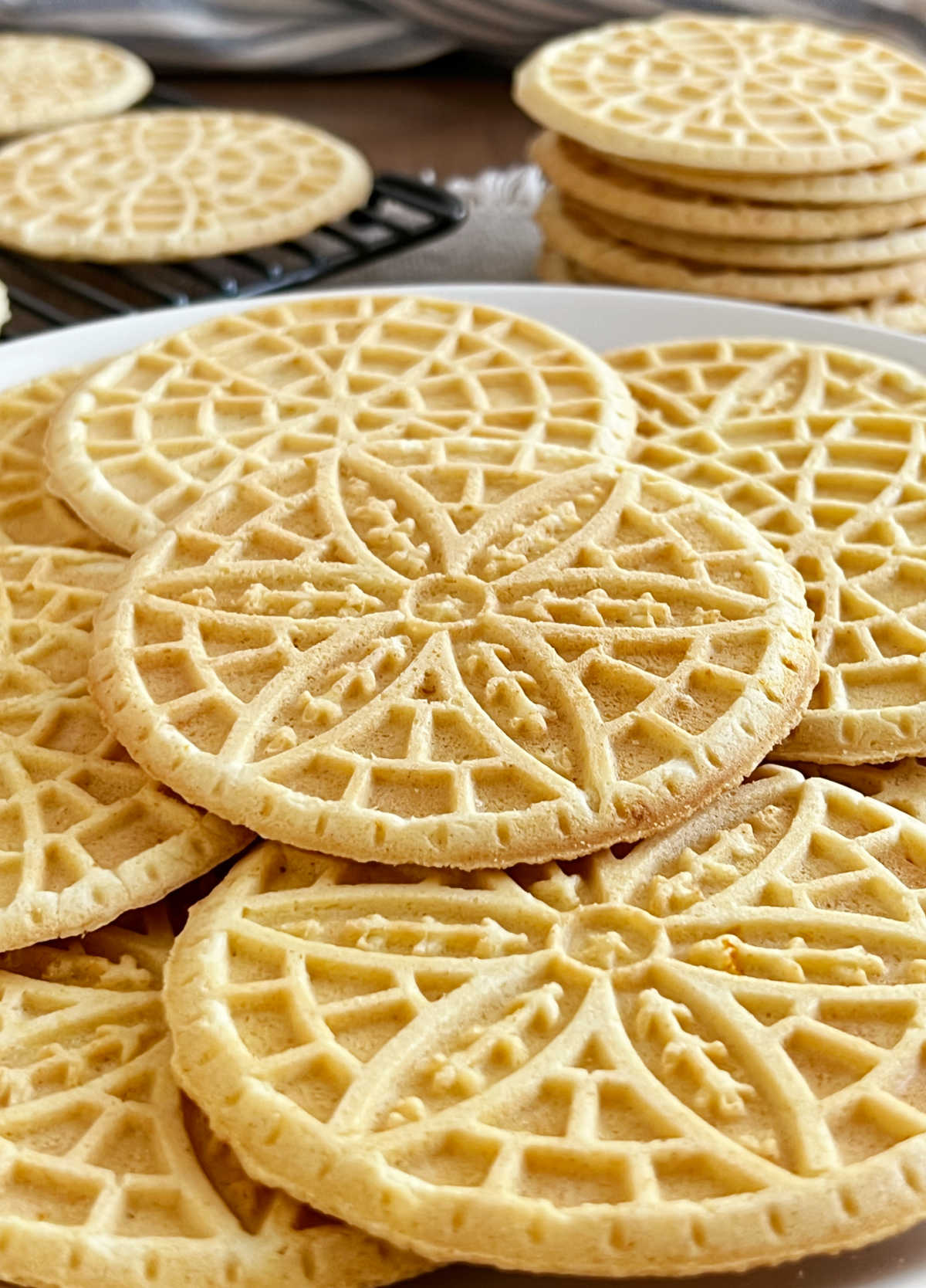 stacks of homemade pizzelle cookies with flower design on the table.