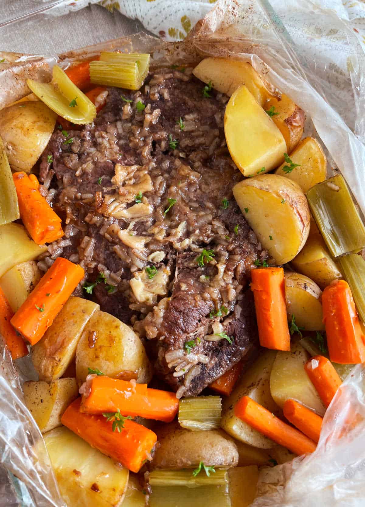 beef pot roast in oven bag with potatoes, carrots and celery.