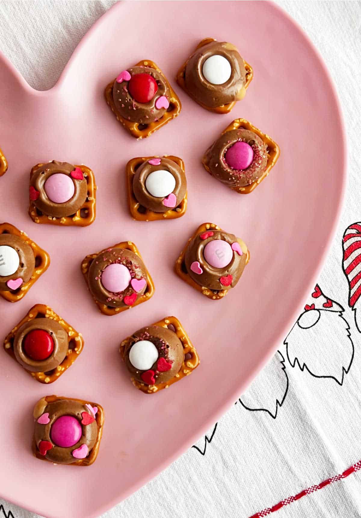 Rolos pretzel treats with Valentine's day candies on pink plate.