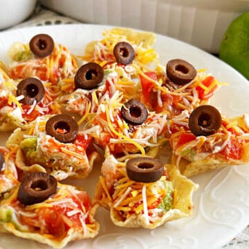 seven-layer dip served in individual tortilla chips scoops on a platter.