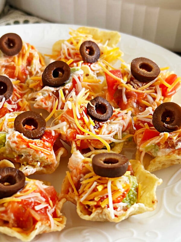 seven-layer dip served in individual tortilla chips scoops on a platter.