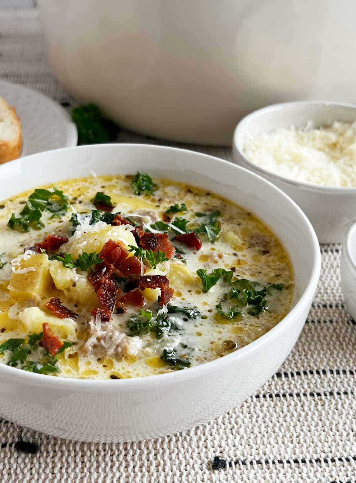 zuppa toscana soup with potatoes, sausage, bacon and kale in white bowl.