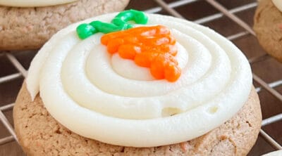 carrot cake mix cookies with cream cheese frosting and iced carrot on top.