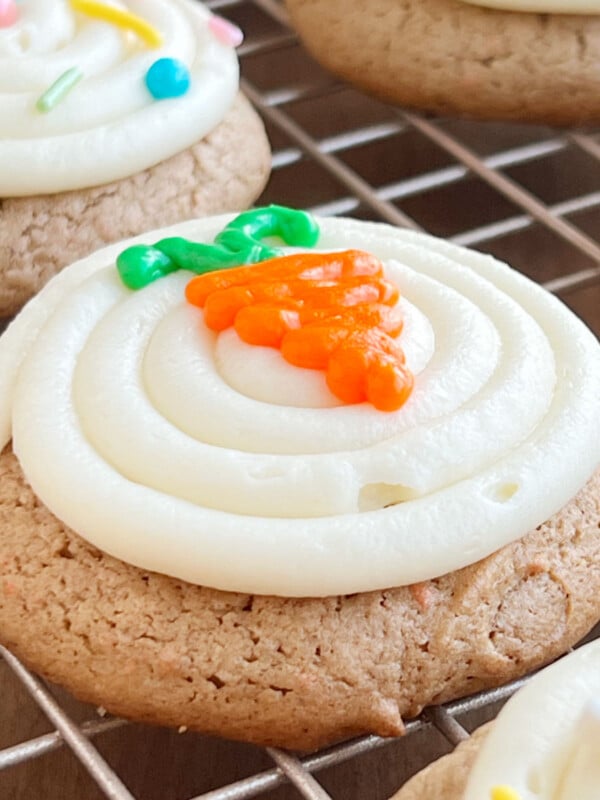 carrot cake mix cookies with cream cheese frosting and iced carrot on top.