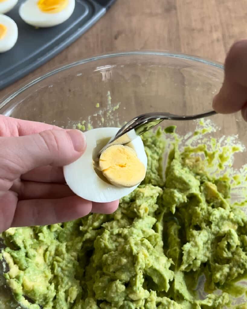 spoon egg yolk into mashed avocados.