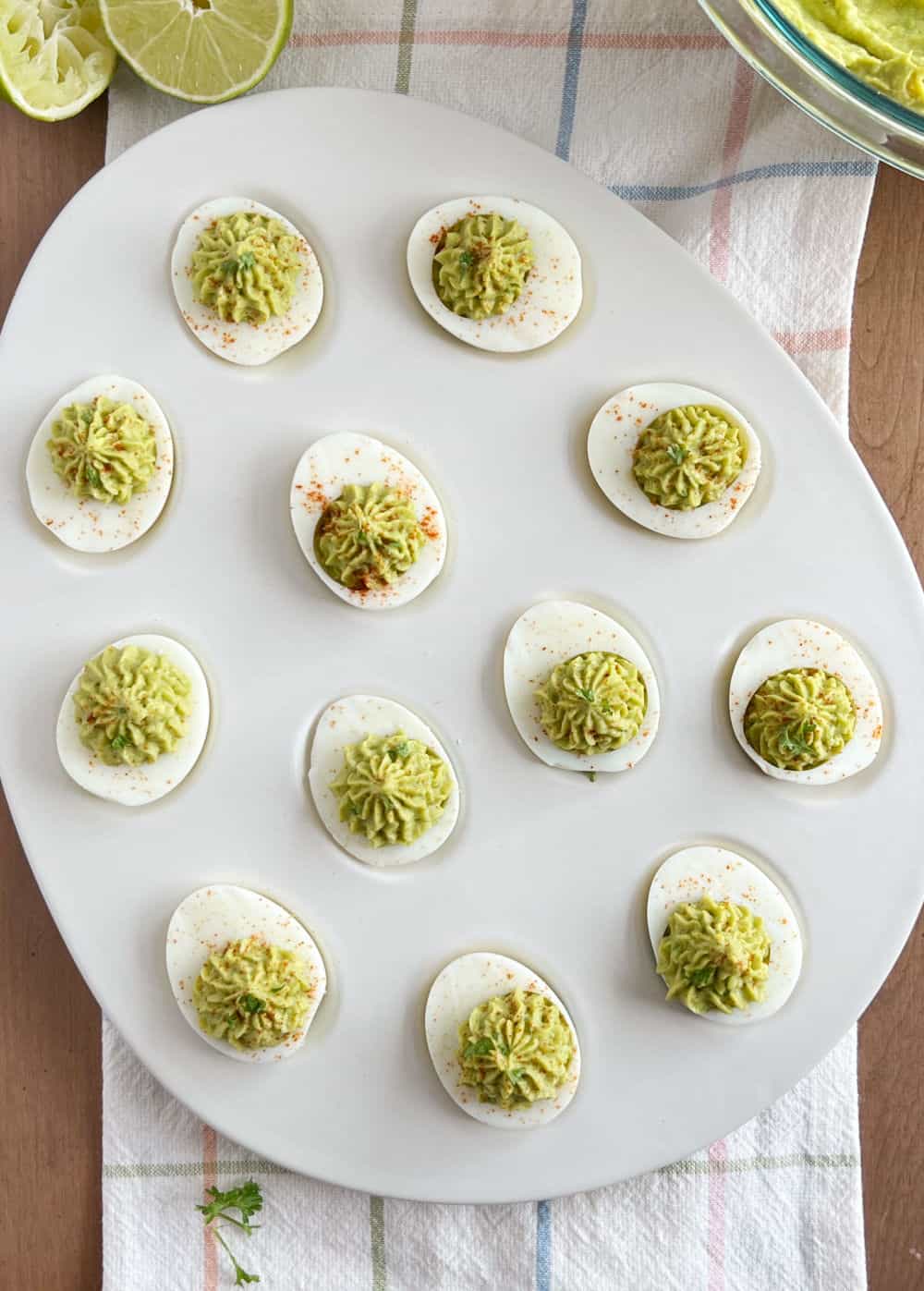 avocado deviled eggs with cilantro and paprika in a serving platter.