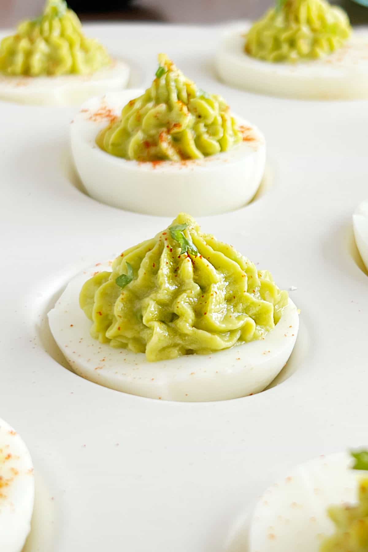 tray of guacamole deviled eggs with paprika.
