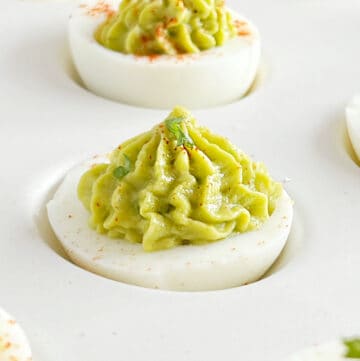 guacamole deviled eggs with piped avocado filling.