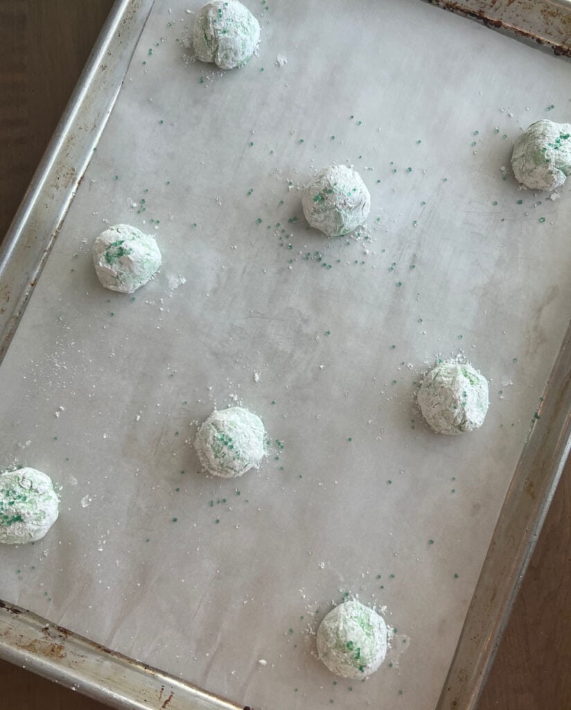 green cookie dough balls on baking sheet.