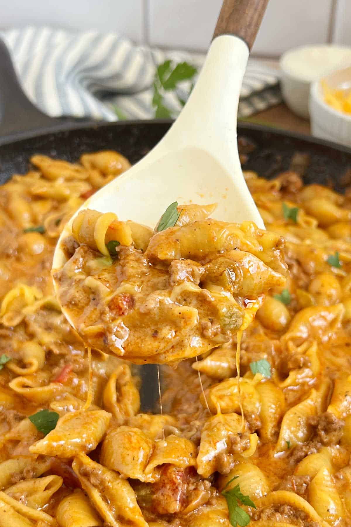 taco pasta in cheese sauce on serving spoon.