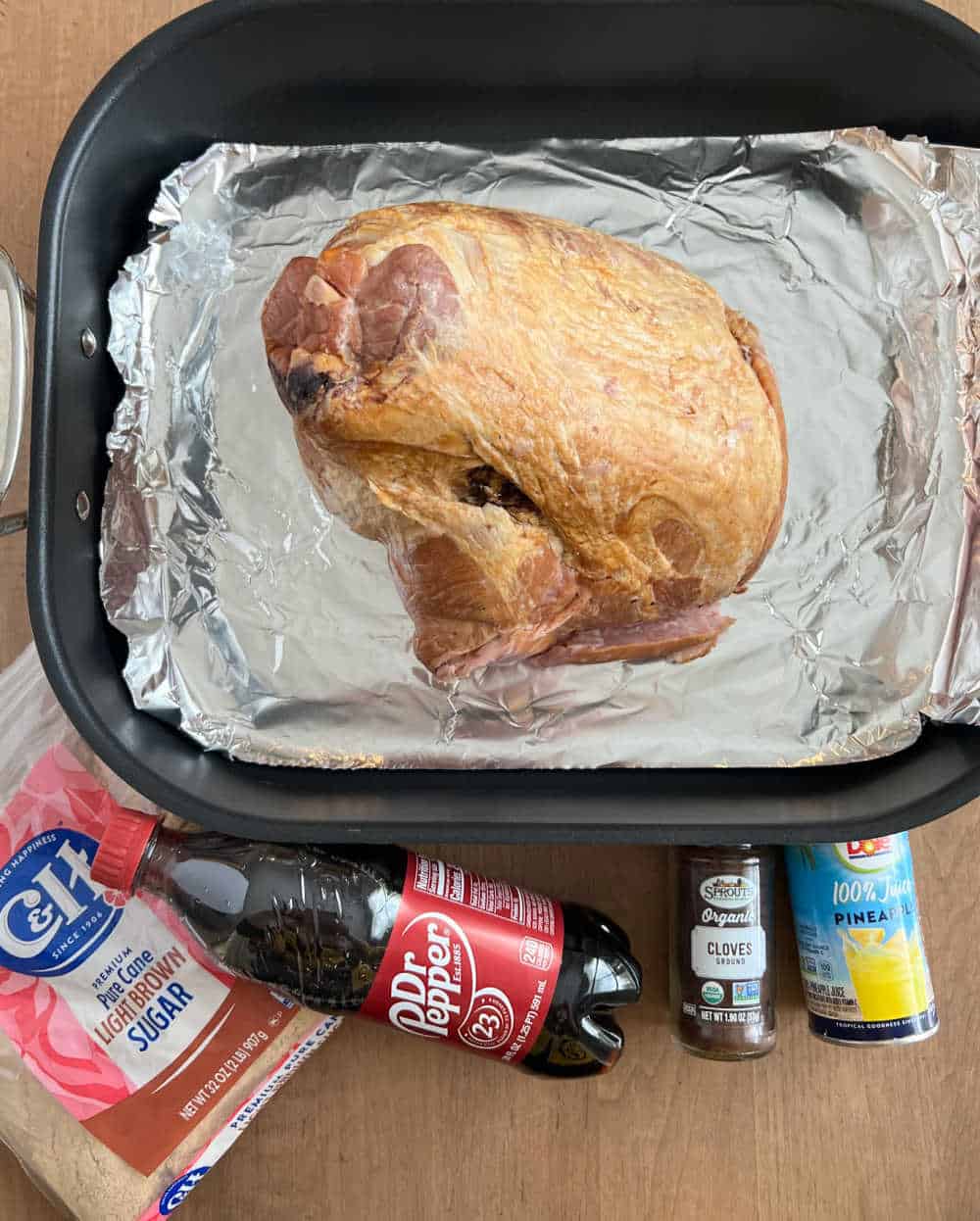 ham in roasting pan with brown sugar, dr pepper, cloves and pineapple juice.