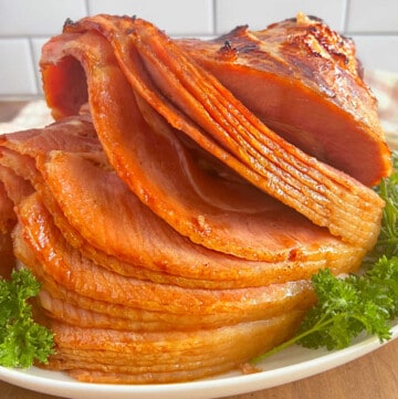 spiral cut baked ham with Dr Pepper glaze on a platter with parsley.