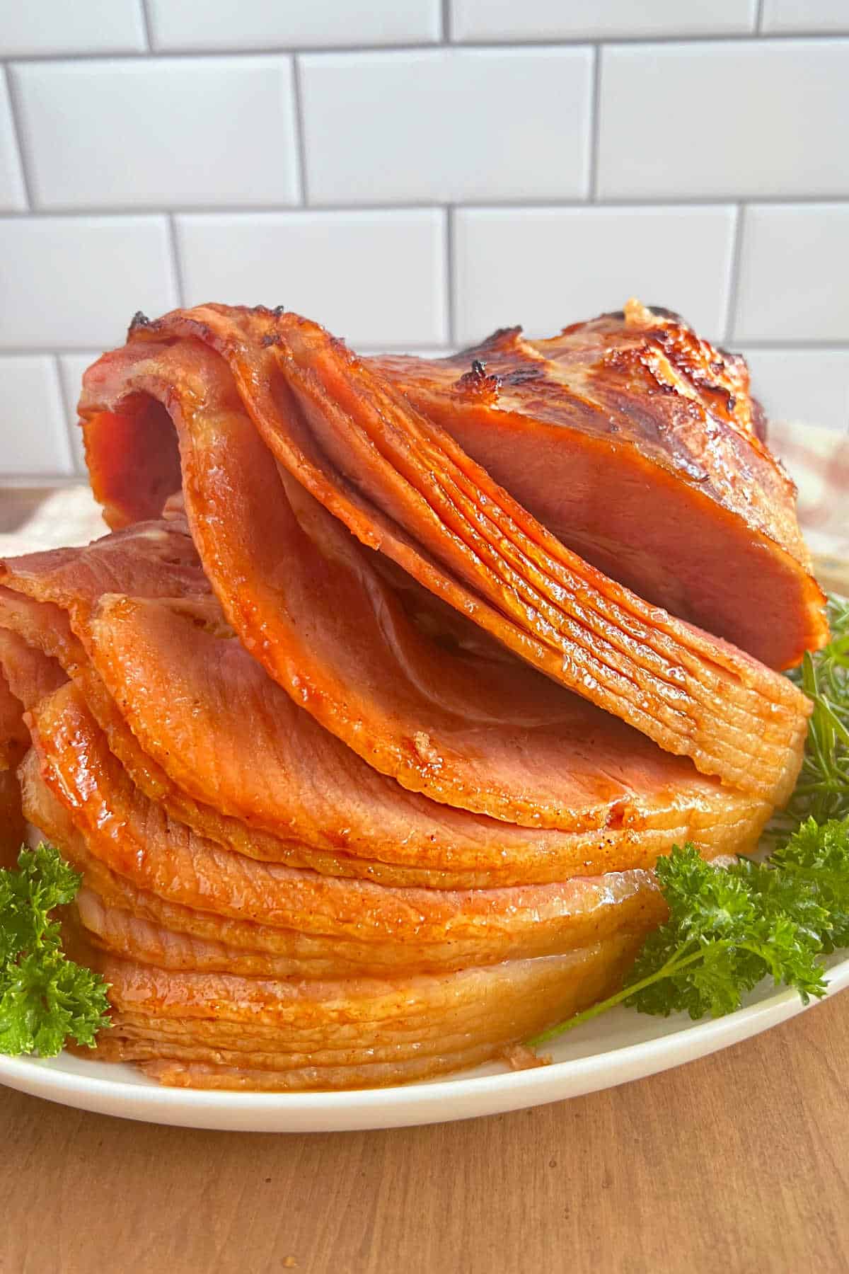 spiral cut baked Dr Pepper ham on a platter with fresh parsley.