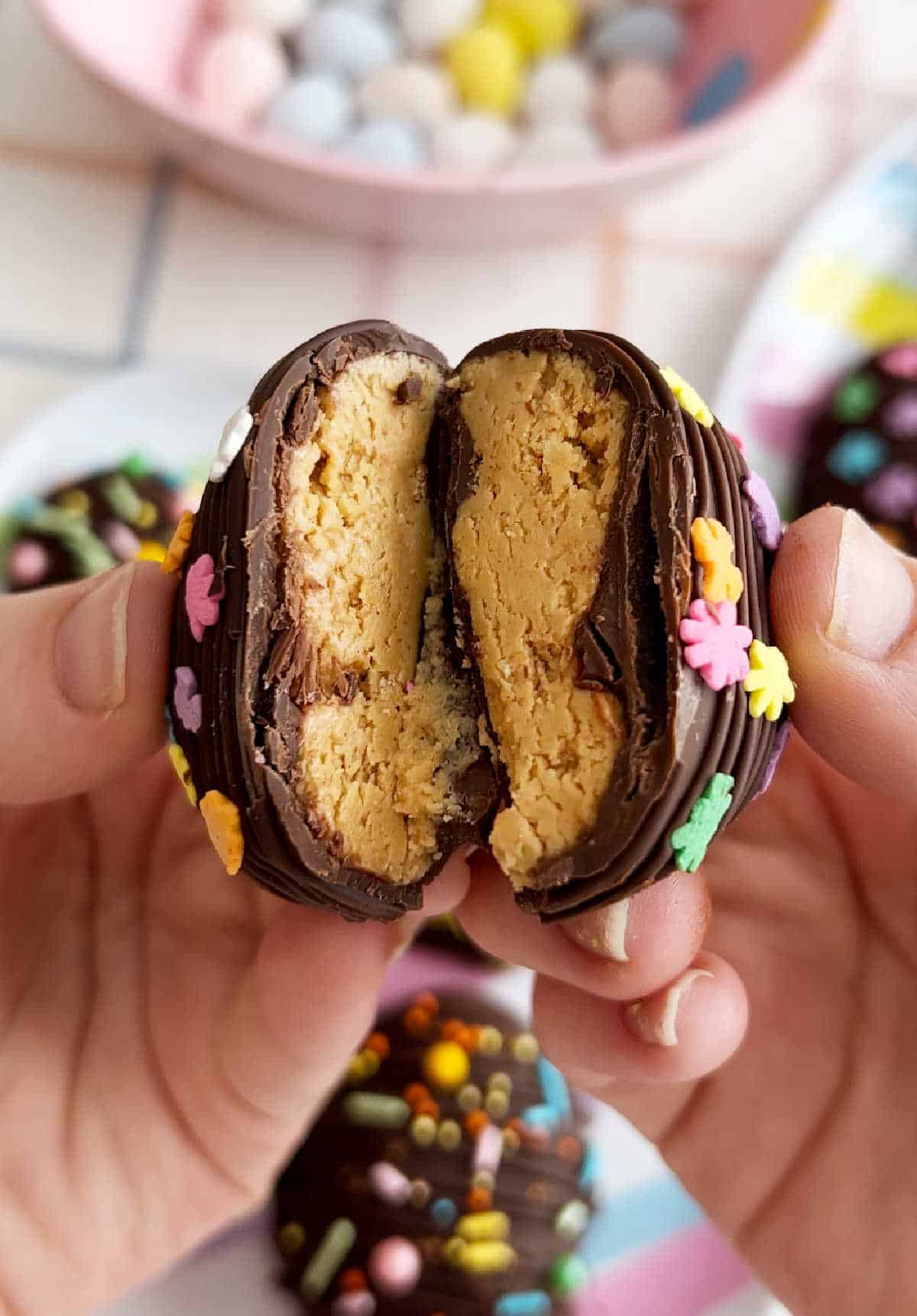 chocolate peanut butter Easter egg cut in half in hand.