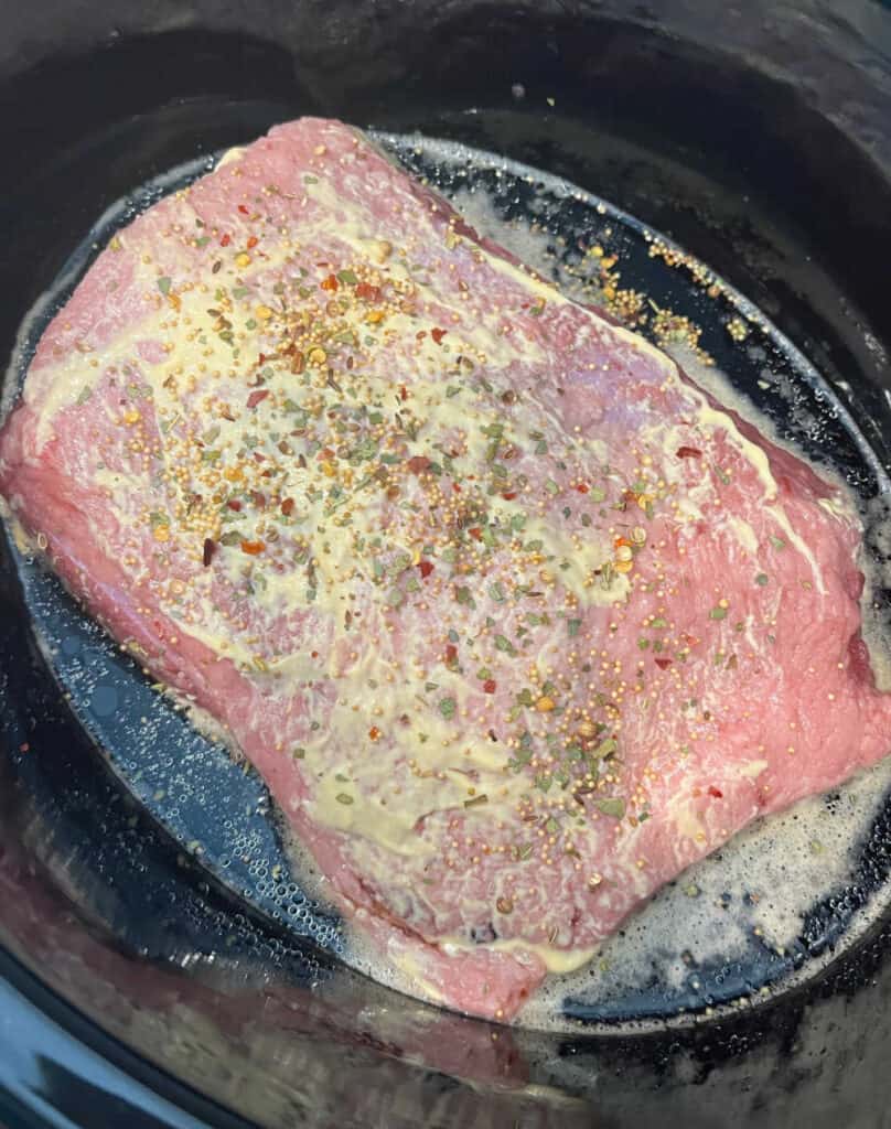 corned beef brisket in slow cooker with mustard and Guinness.