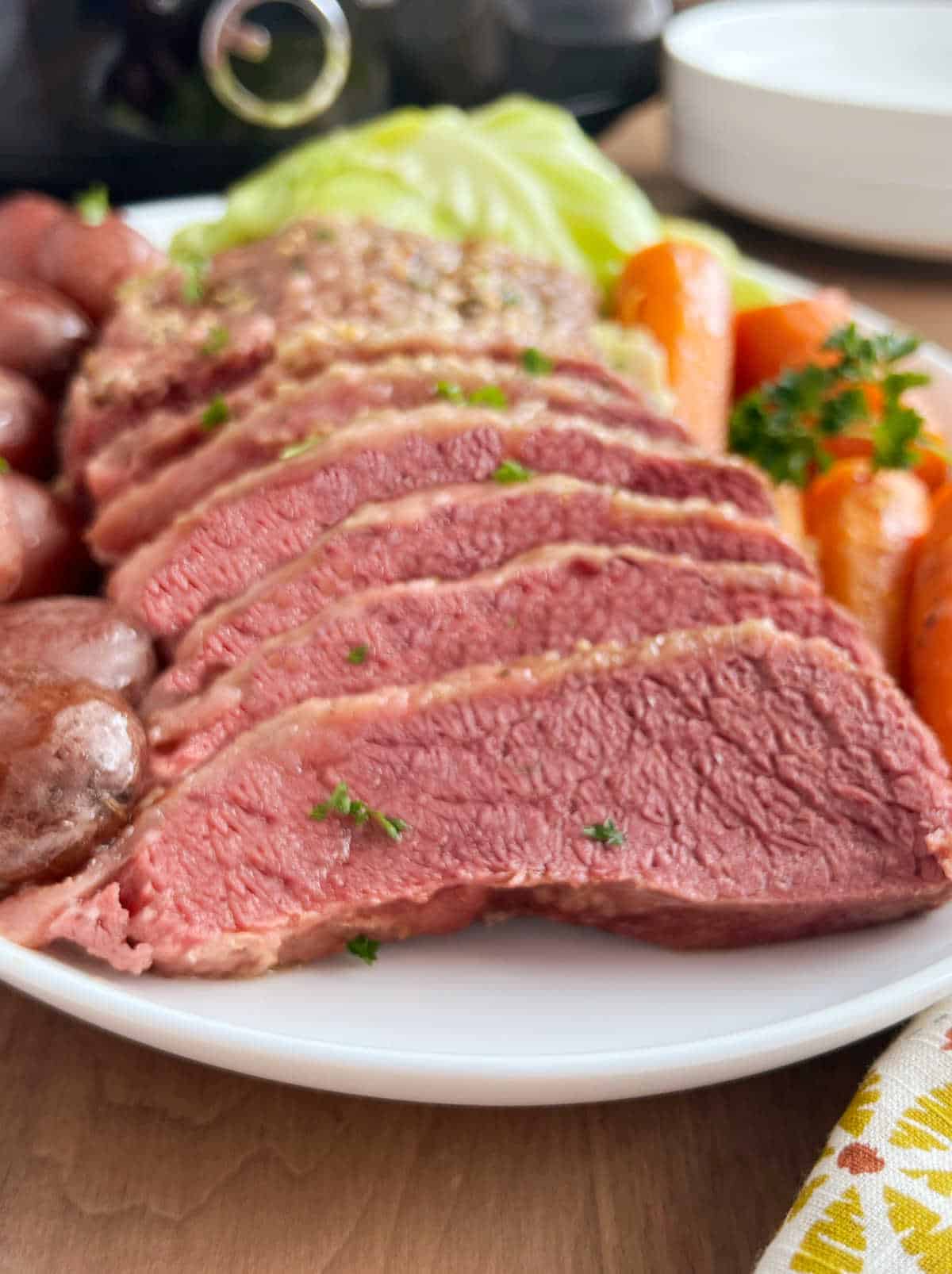 platter with sliced corned beef and vegetables by crockpot