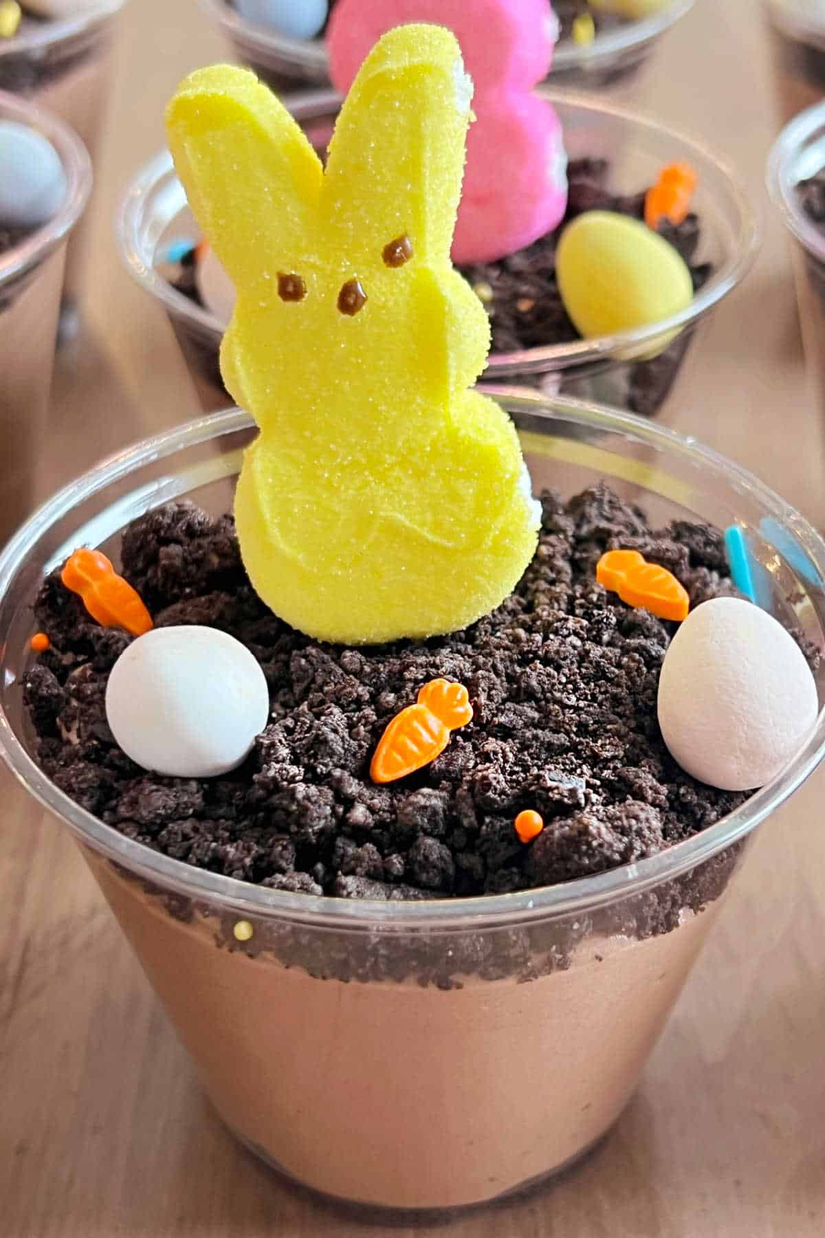 Yellow peeps bunny with candy carrots and eggs in pudding cup.