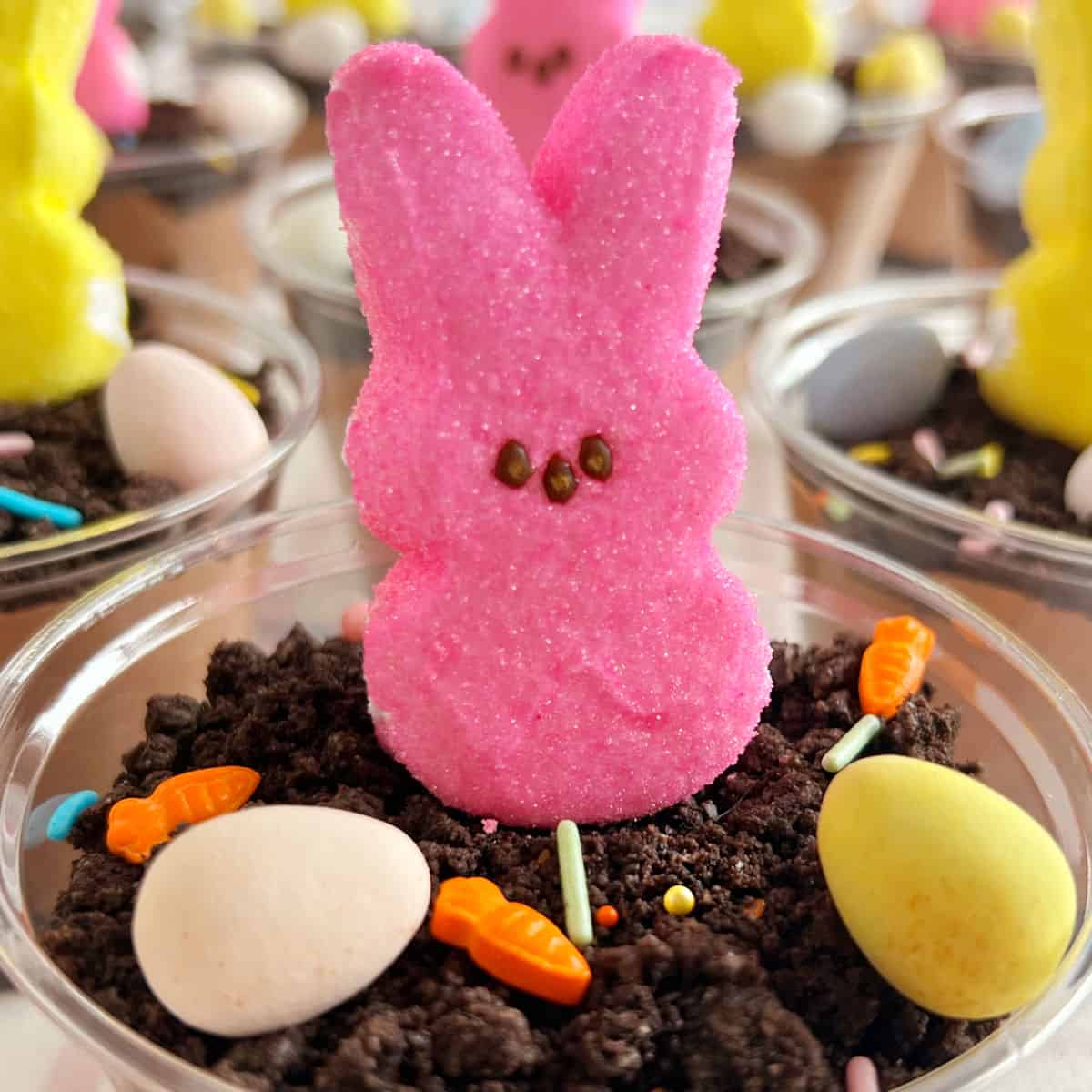 Easter dirt cups with bunny peeps, crushed Oreo cookies and candy eggs.