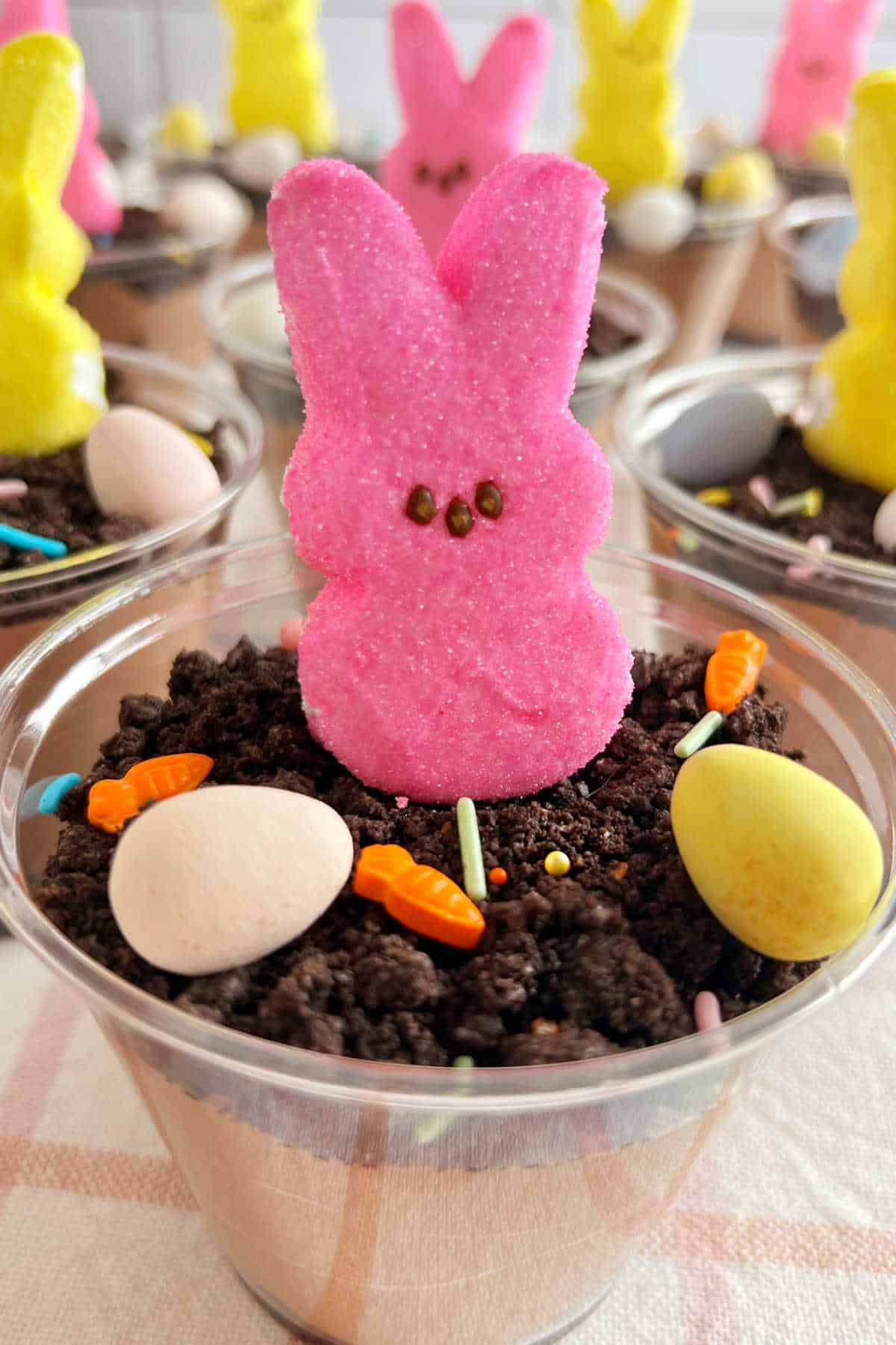 Easter pudding cups with pink peeps bunny and candy eggs in Oreo dirt.