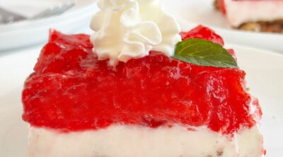 slice of strawberry pretzel salad with whipped cream on a plate.