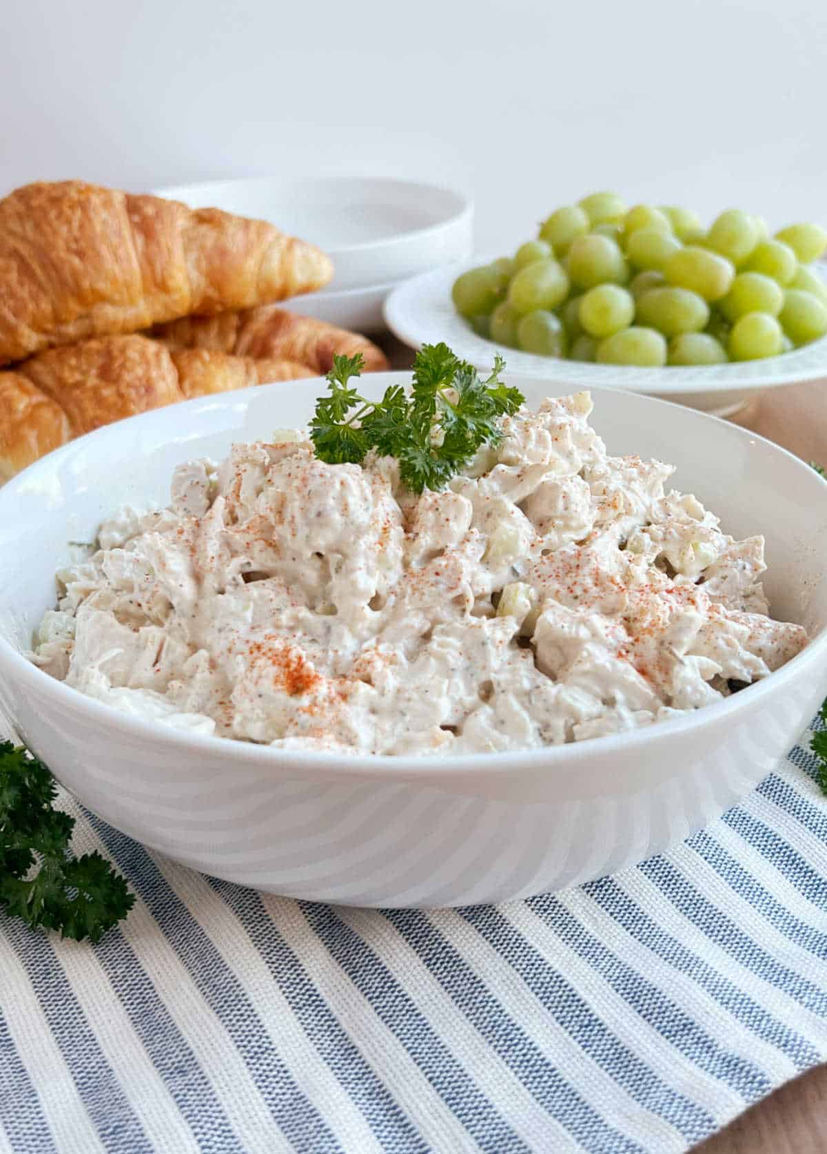 simple chicken salad bowl with croissants and grapes on the table.