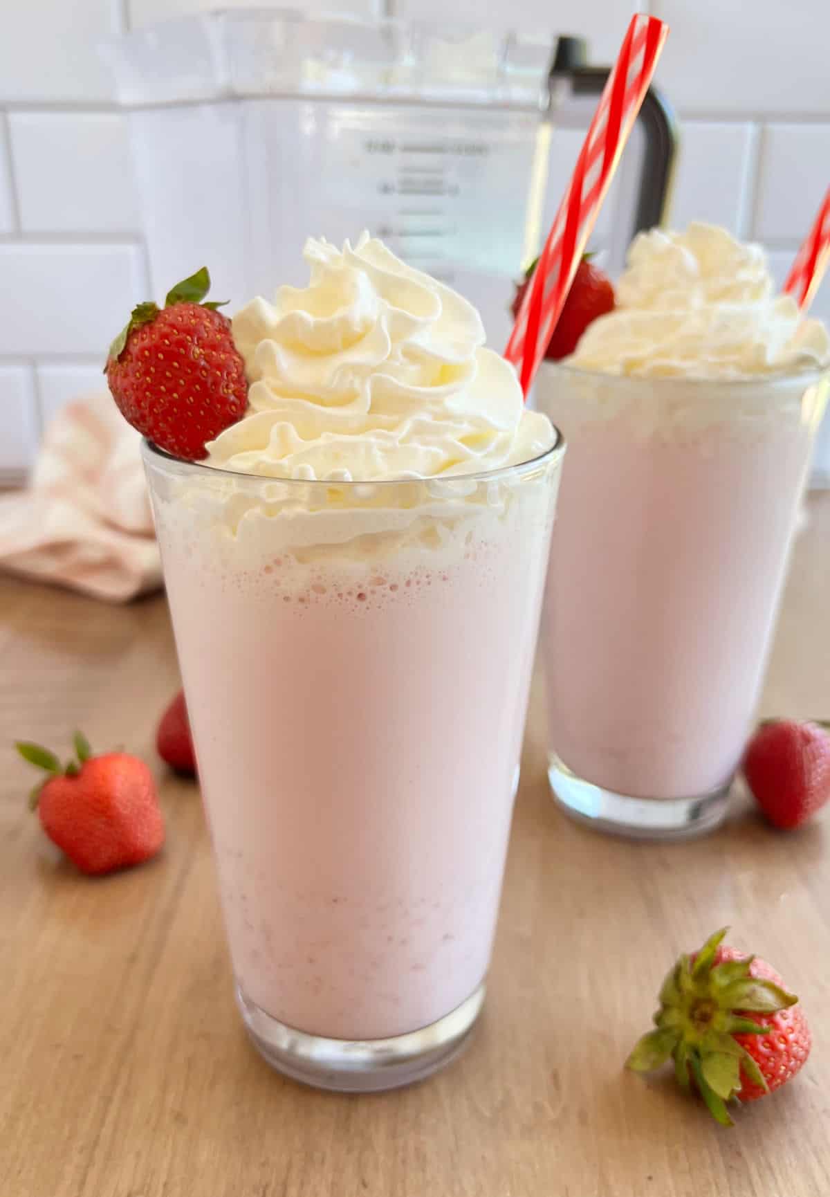 strawberry milkshakes with whipped cream and strawberries in tall glass.