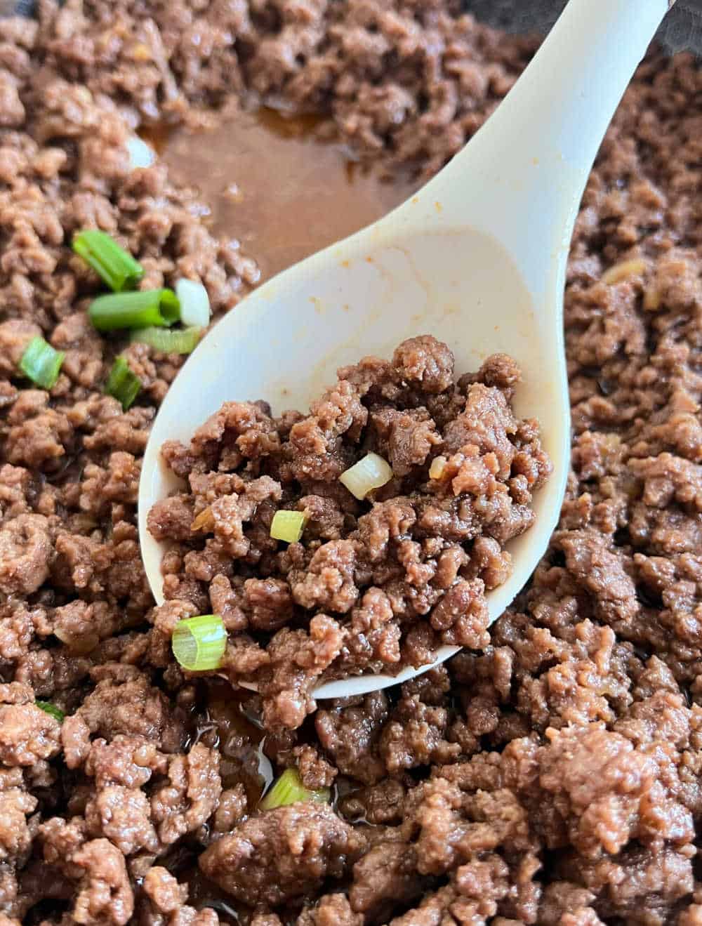 serving spoon with Korean ground beef over skillet.