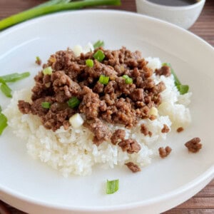 Korean ground beef with green onions over rice on a plate.