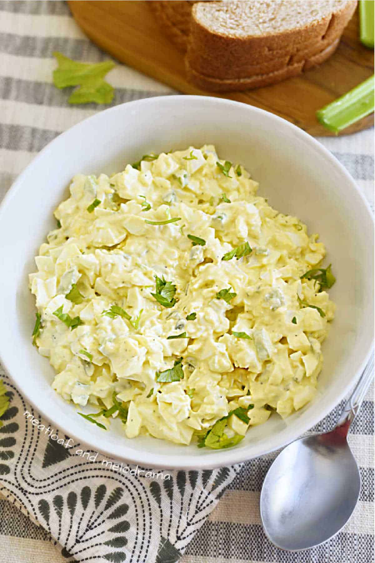 bowl of egg salad garnished with celery leaves.