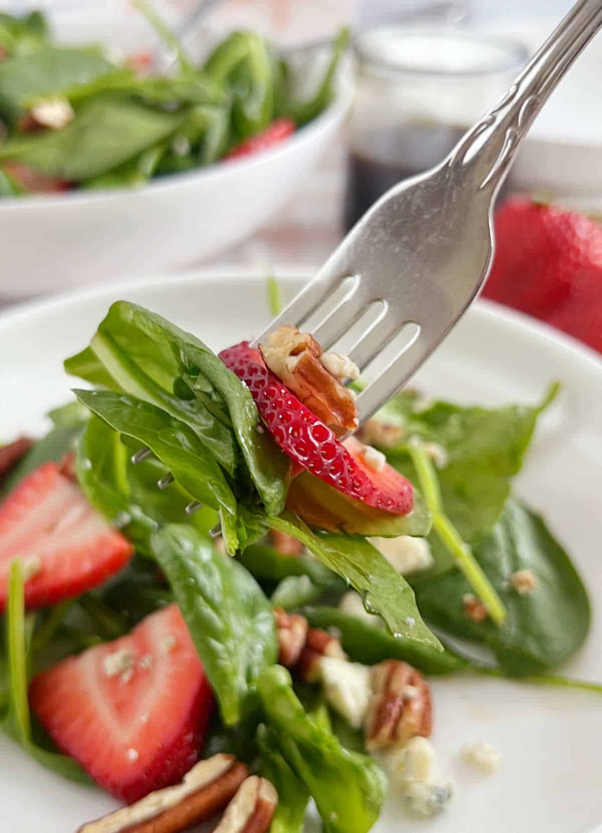 strawberry spinach salad on a fork.