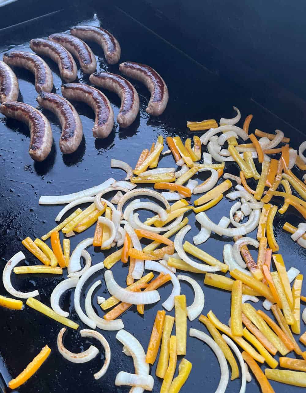 Italian sausage, peppers and onions on flat top grill