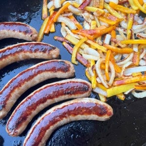 Italian sausages with peppers and onions on blackstone griddle.
