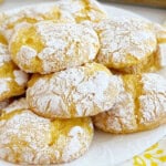 lemon crinkle cookies with powdered sugar stacked on plate.
