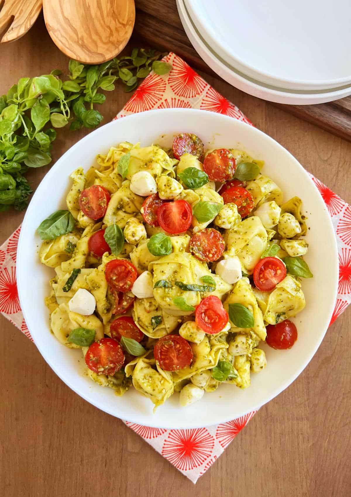 bowl of tortellini salad with pesto, tomatoes and mozzarella.